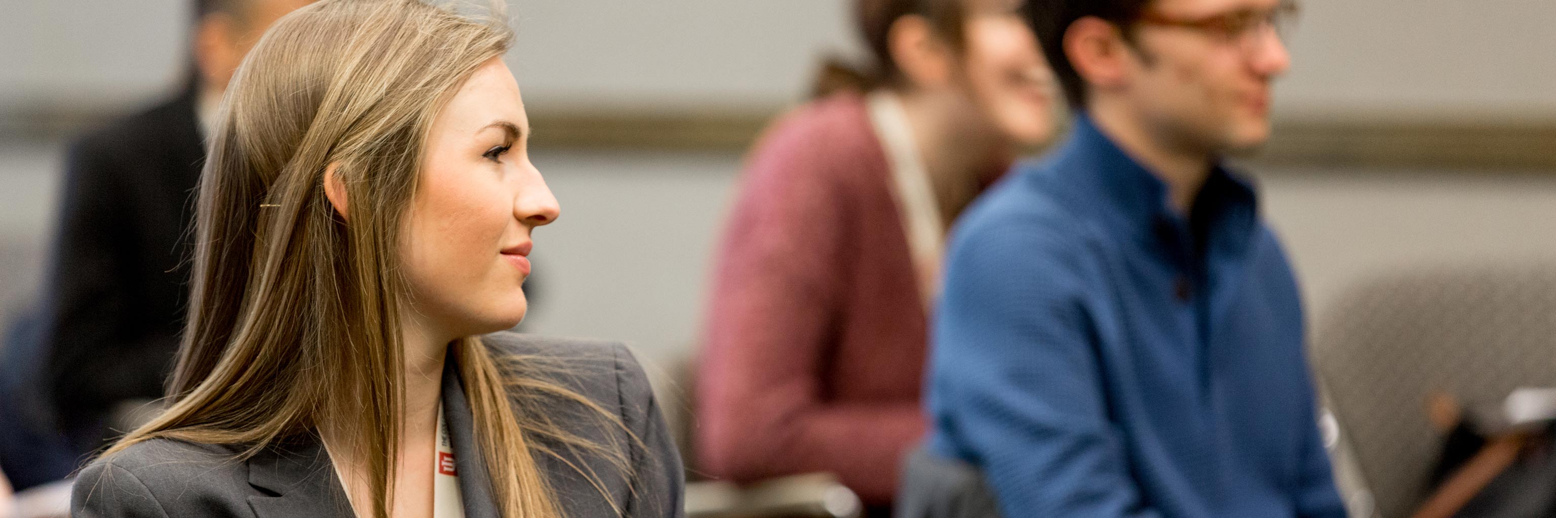 Profile of a female student in a suit watching something across the room 