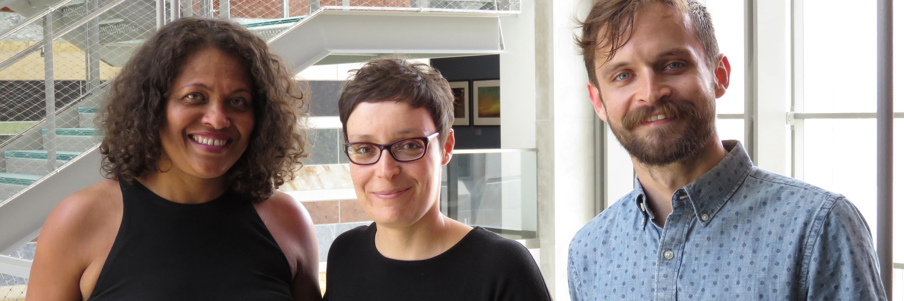 Three members o the Spanish and Portuguese Department smile for the camera in the Global and International Studies Building 