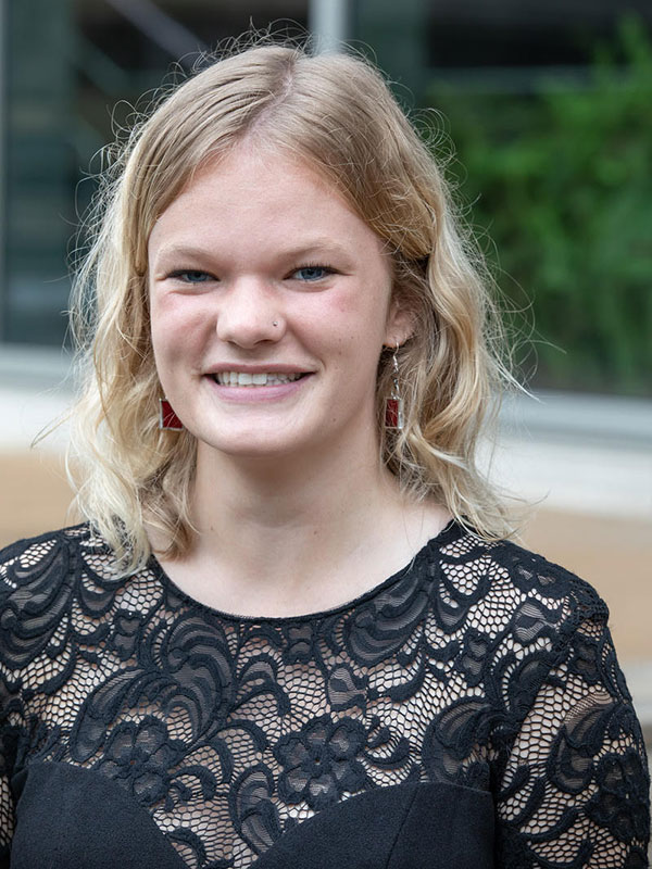 A headshot of Jessica Morris, who wears a black shirt and poses outside.