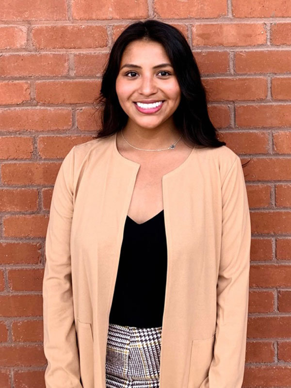 Leslie Del Carpio poses in a beige sweater and a black shirt.