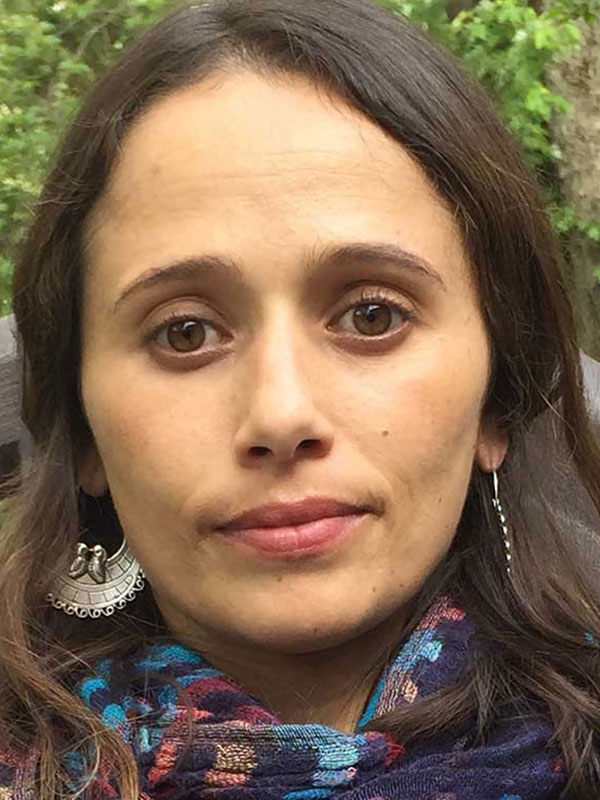 A headshot of Professor Olimpia E. Rosenthal, who wears a colorful scarf and poses outside.
