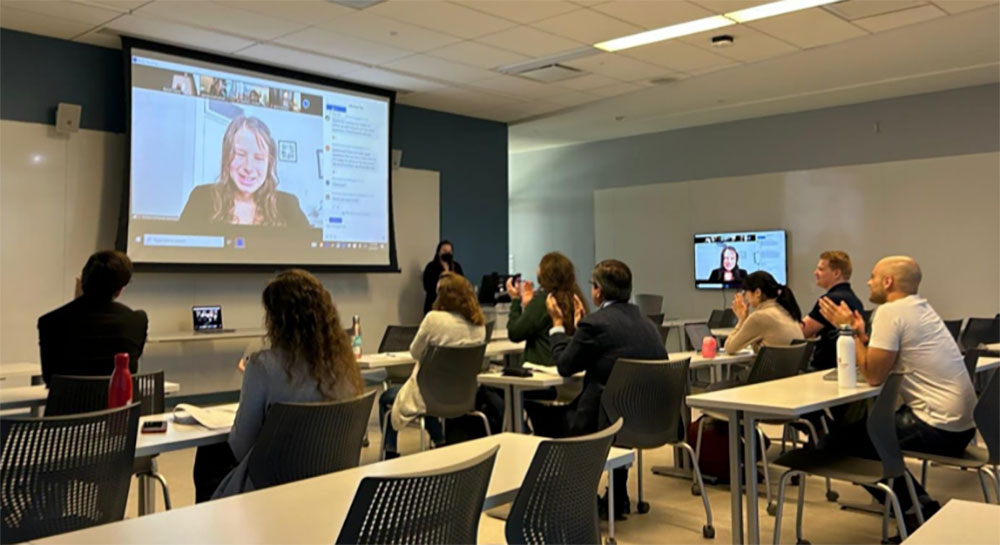 Conference attendees listen to a Zoom lecture in a classroom.