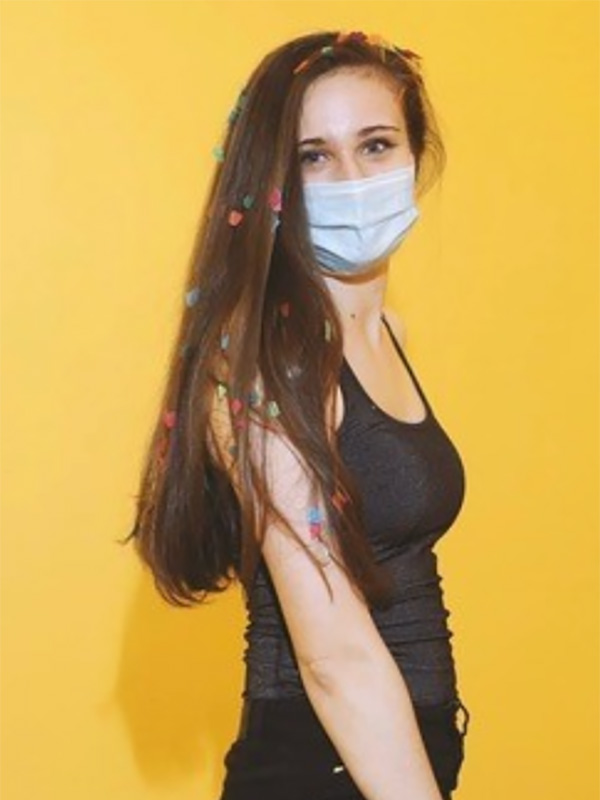 A photo of Jackie Hentz, who wears a gray shirt and poses against a bright yellow background.