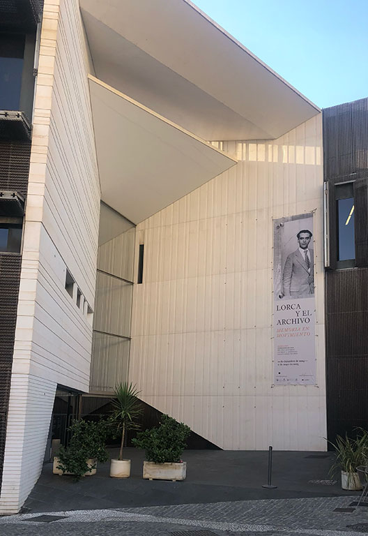 Exterior of a modern white building with a large vertical banner featuring Federico García Lorca.