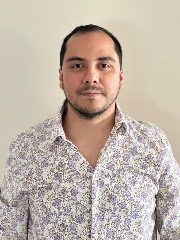 Portrait of a person wearing a light-colored floral shirt, standing against a plain background.